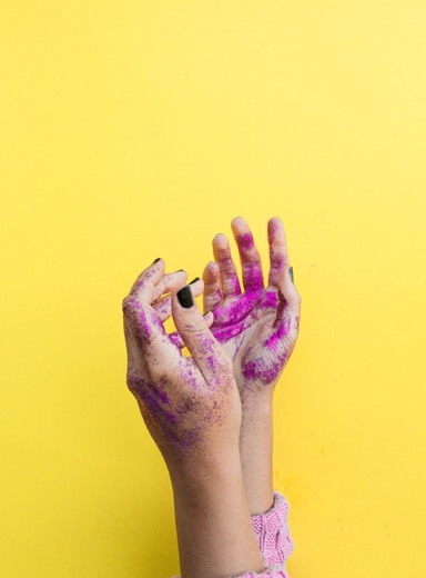 artsy hands covered with paint on a banana yellow background