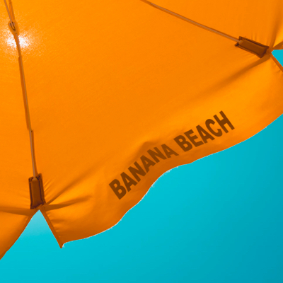 banana beach branded orange beach umbrella against a turquoise sky