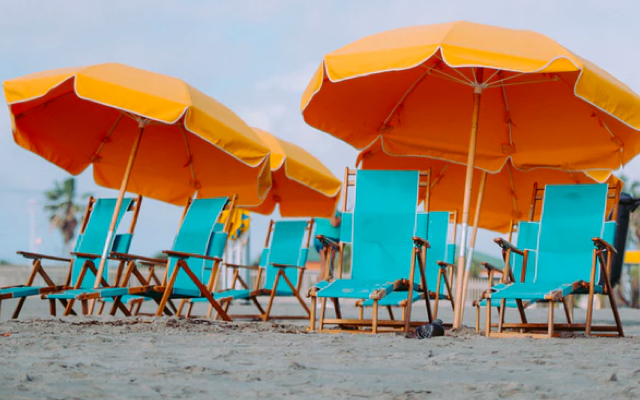 orange beach umbrellas and turquoise beach chairs on the beach