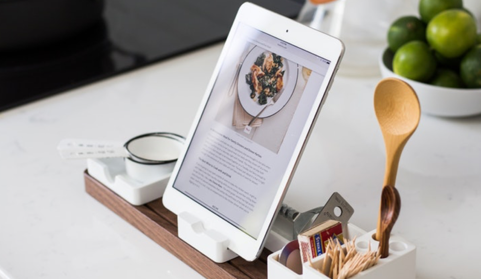 closeup shot of a white table with an ipad on a minimalistic stand filled with simple utensils